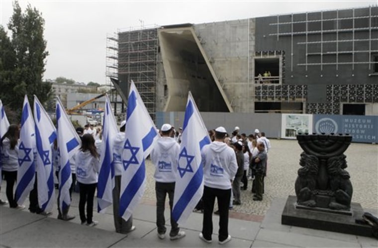 Young Israelis stand Monday in front of the building under construction for the Museum of the History of Polish Jews in Warsaw, Poland.